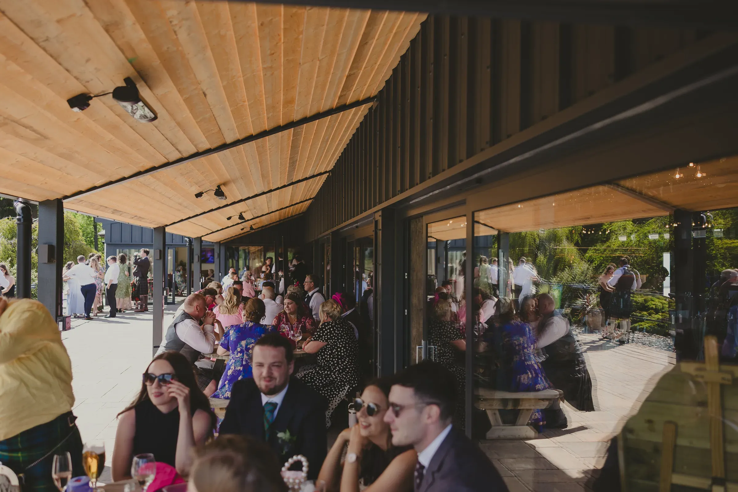 The wedding party enjoys drinks and socializes outside the barn at Glenclova.