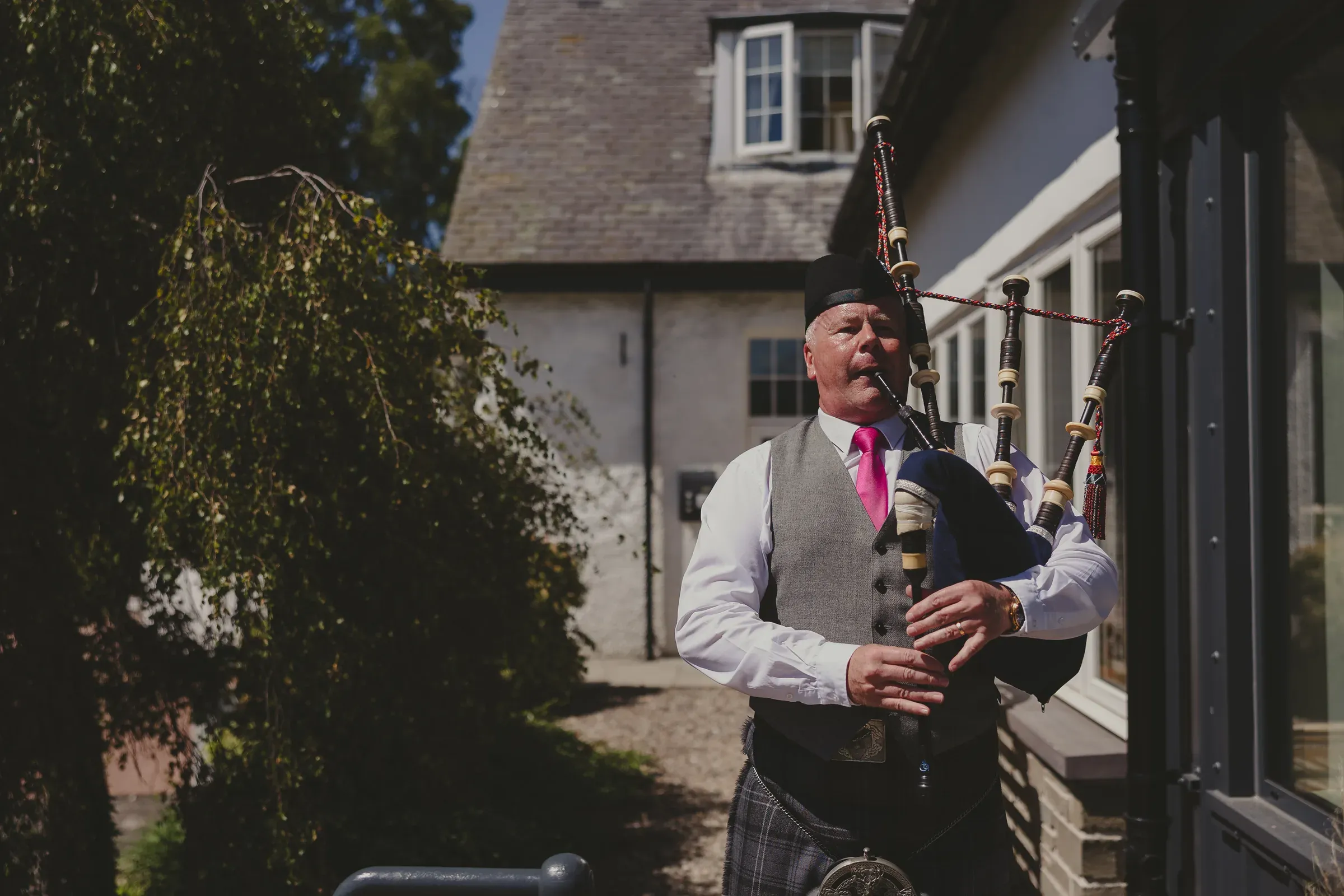 A Scottish man plays the bagpipes outside the front door of the Glenclova hotel.