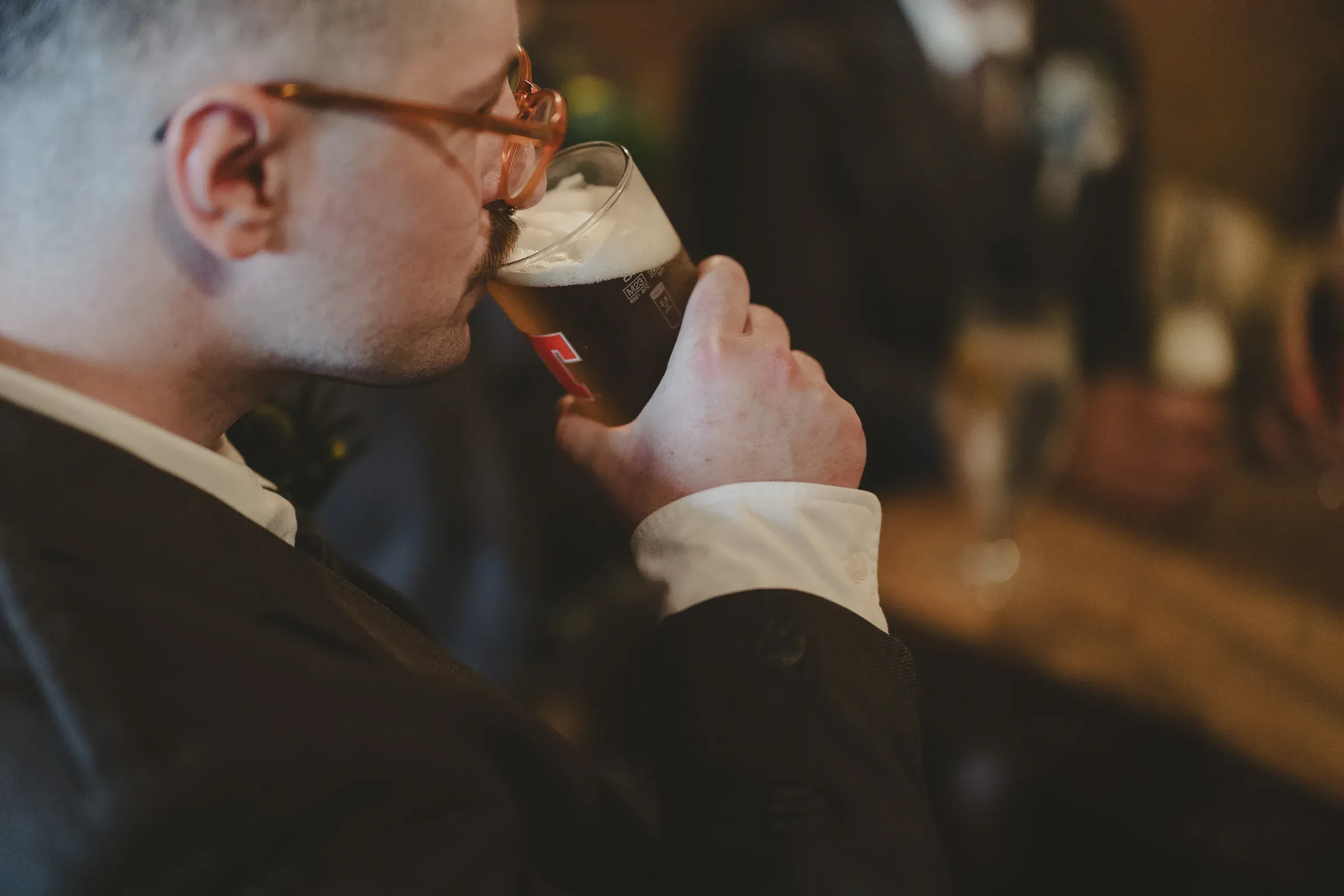 A guest in a suit enjoys a pint of beer at the bar.