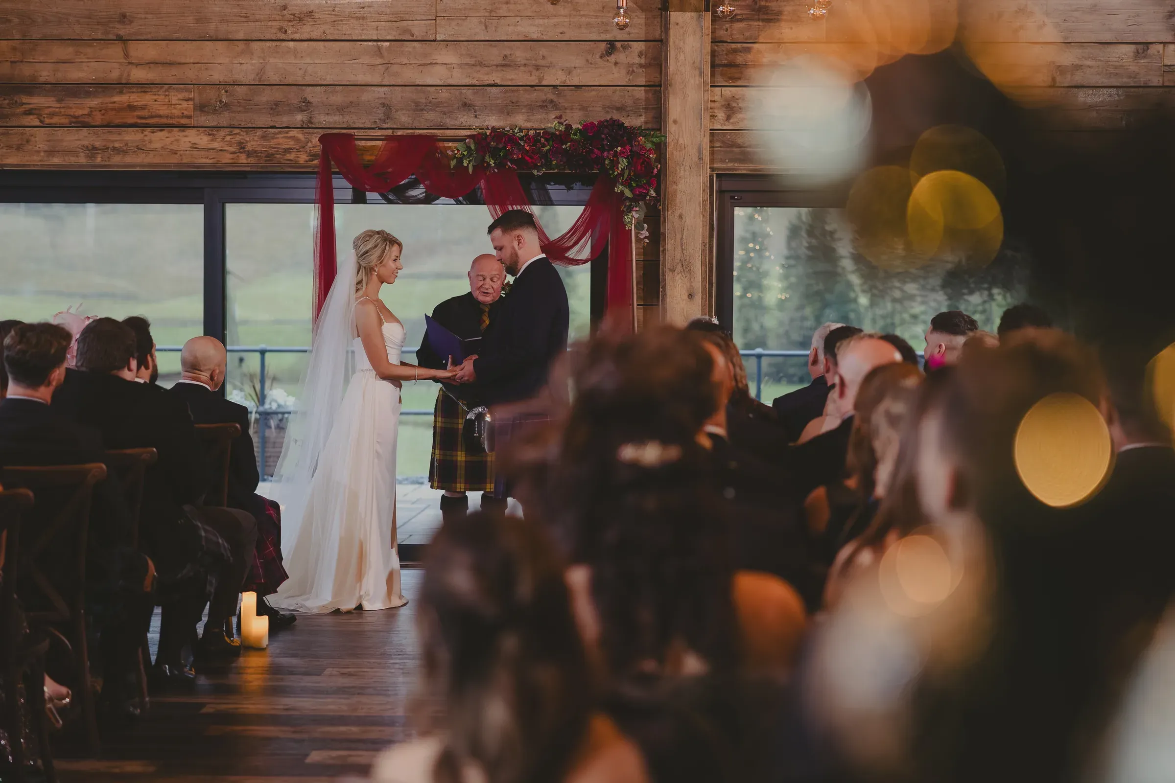 Kevin and Katie exchange vows at the altar inside the barn venue with guests looking on.