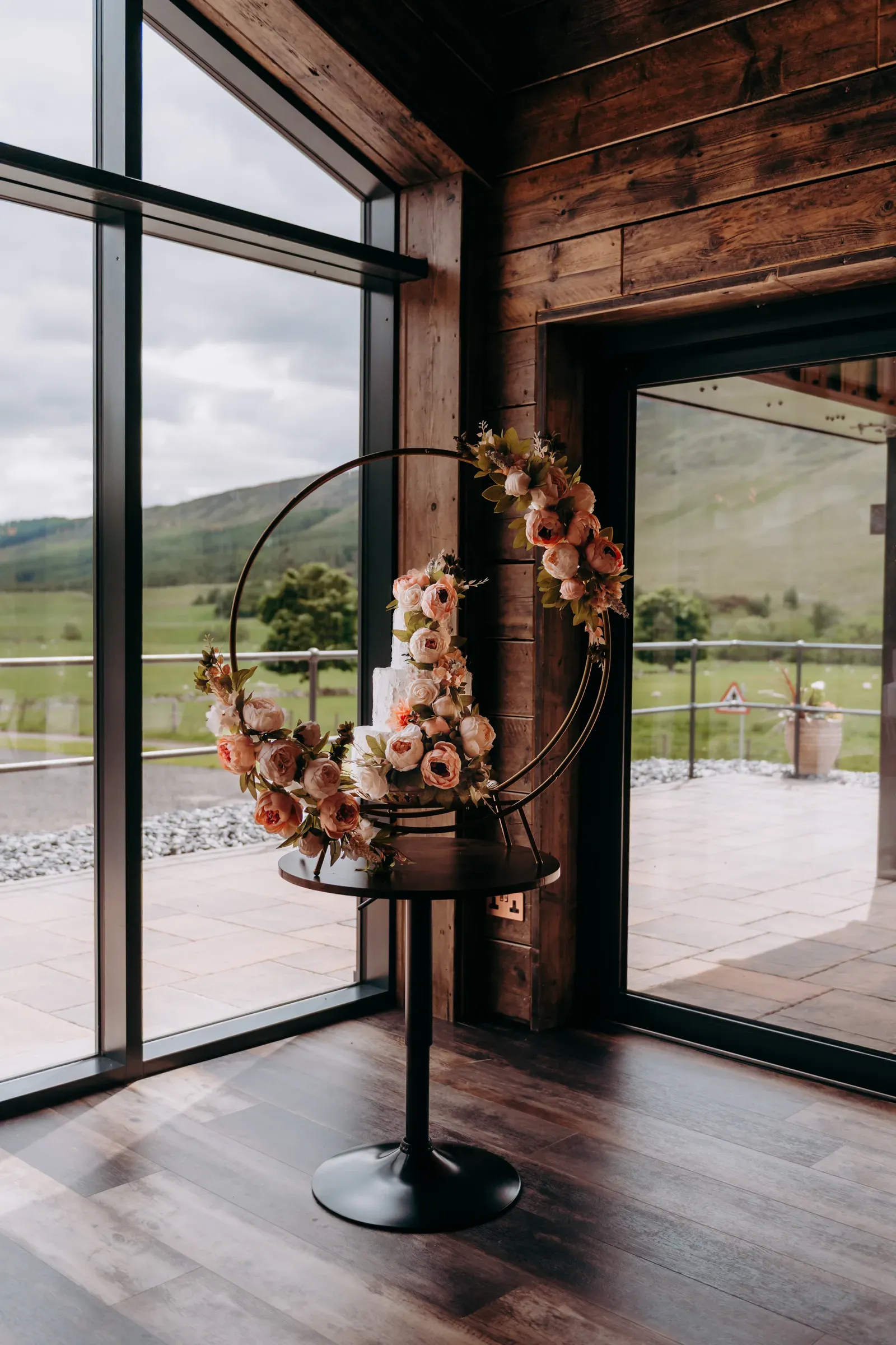 A beautiful floral arrangement displayed on a stand inside the barn at Sam and Cam's wedding.