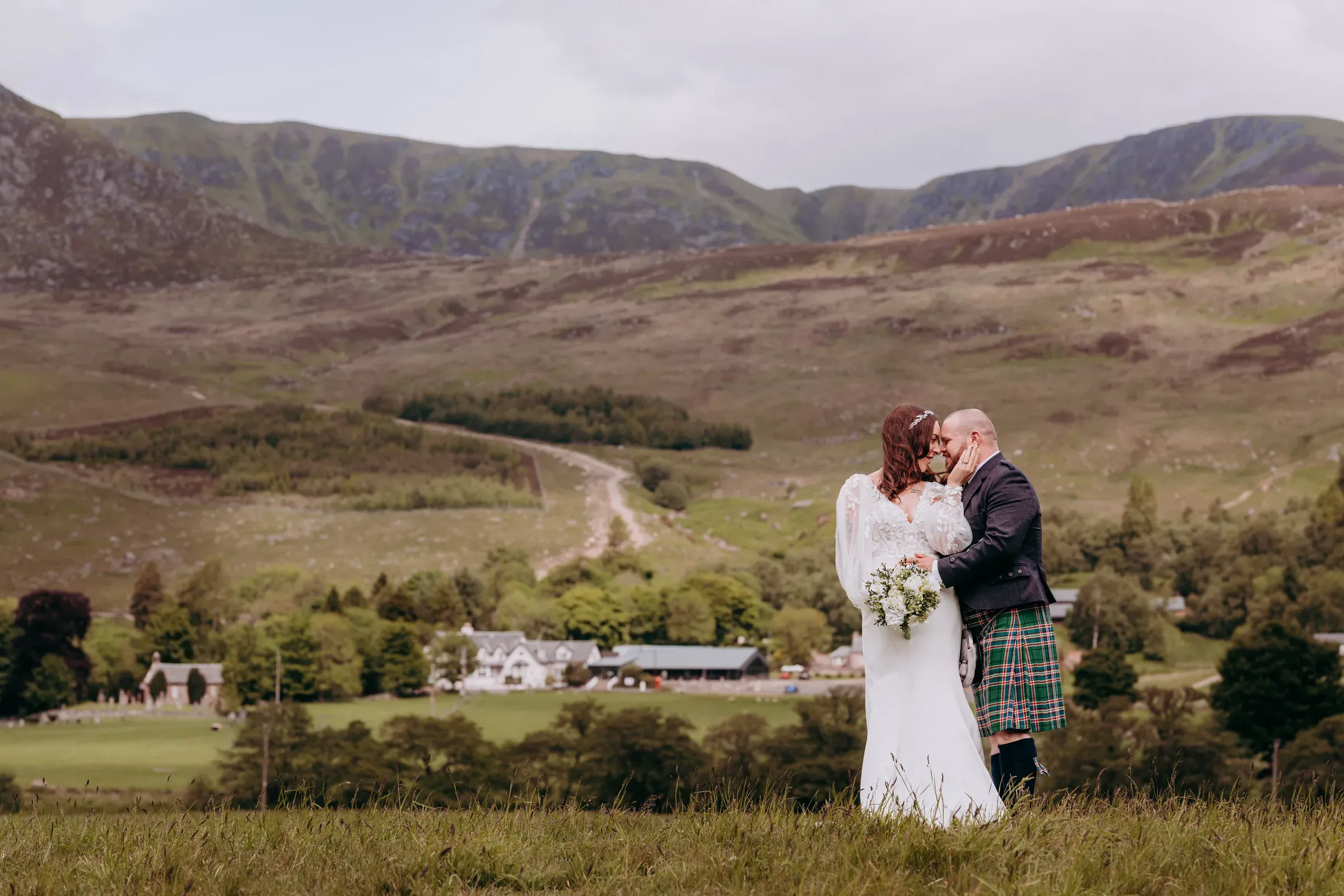 Sam and Cam share an intimate kiss with the Glenclova hotel and the surrounding glen in the background.