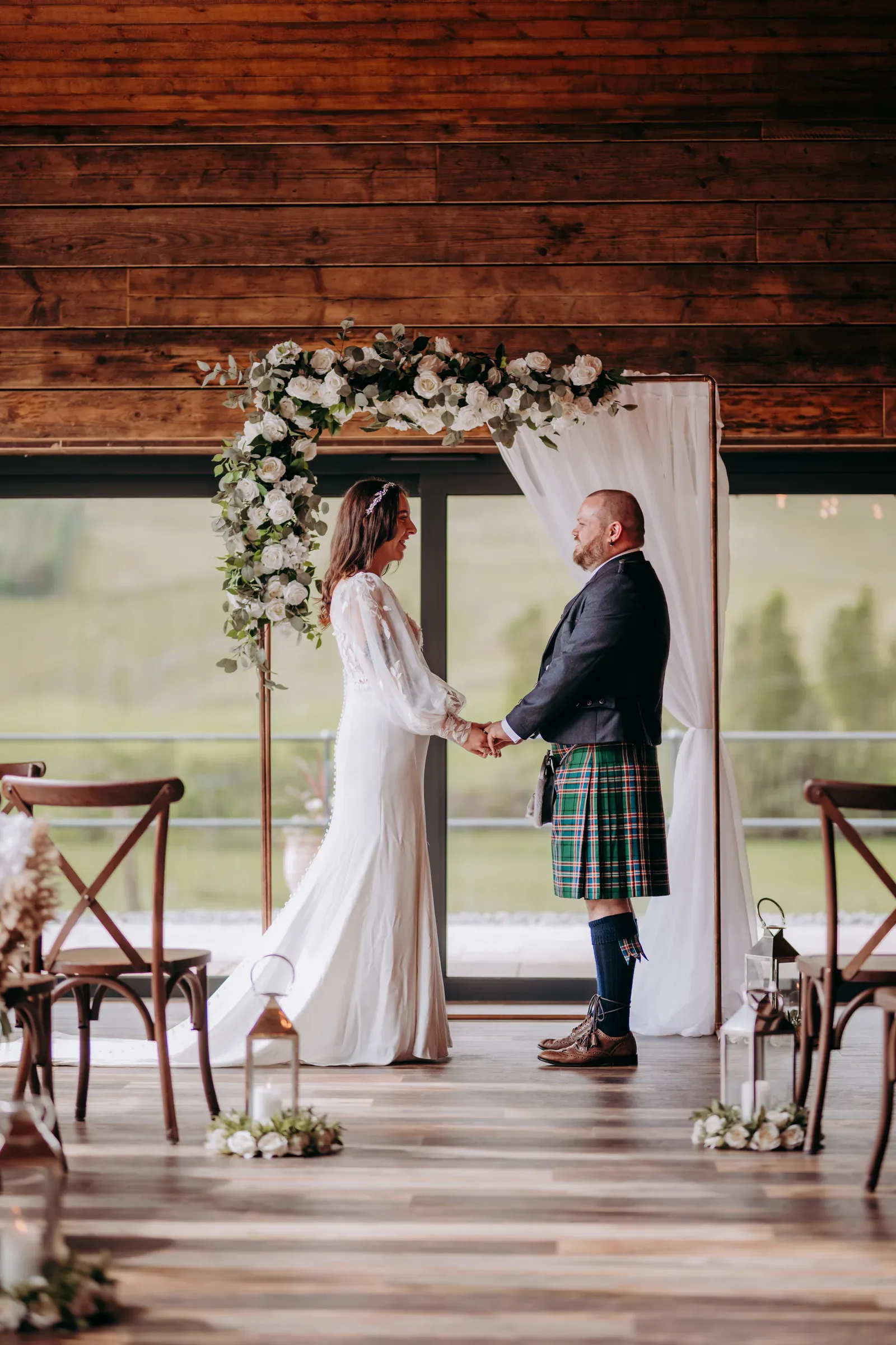 Sam and Cam stand holding hands at the altar inside the barn at Glenclova.