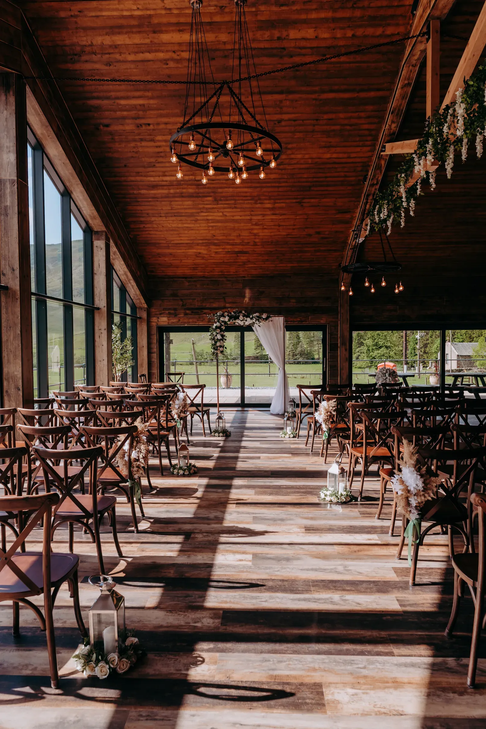 A vertical view of the barn interior set up for a wedding ceremony with warm lighting and no people.