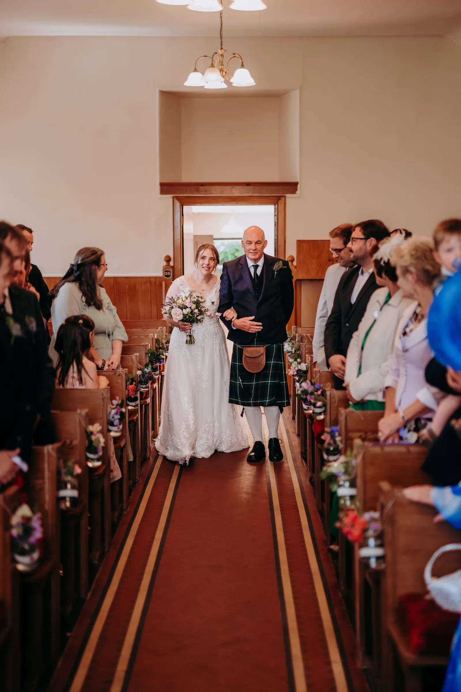 Heather is walked down the aisle by her father inside the kirk during her wedding to Lewis.