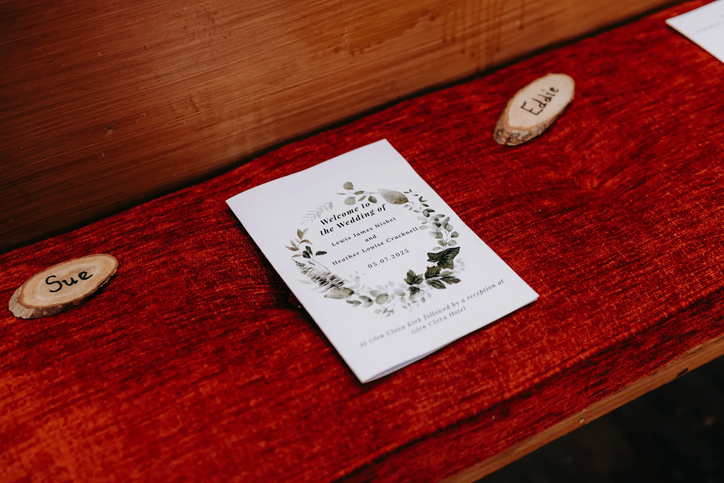 A wedding invitation and personalized wooden name tags rest on a bench inside the Kirk, showcasing how couples can personalize their ceremony space.