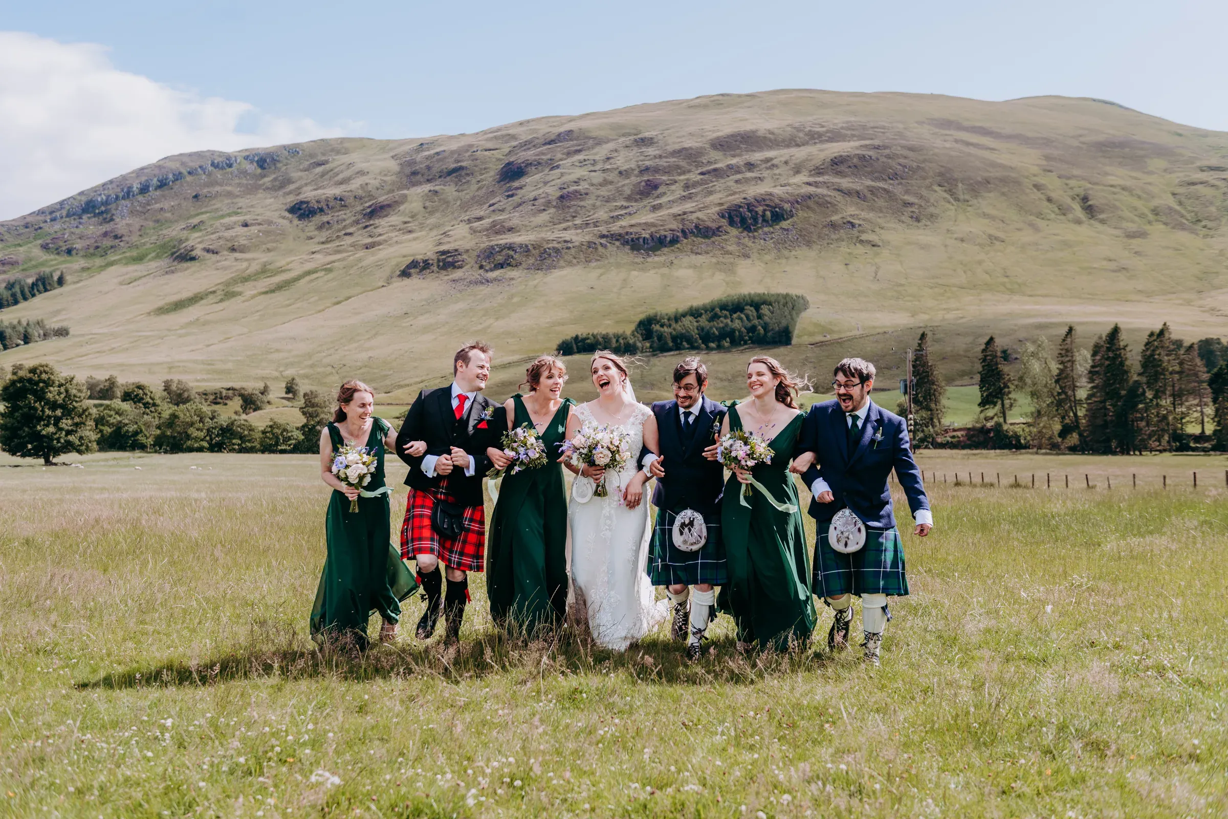 Heather and Louis walk through the Glen with their bridal party in a fun, candid moment after their wedding.