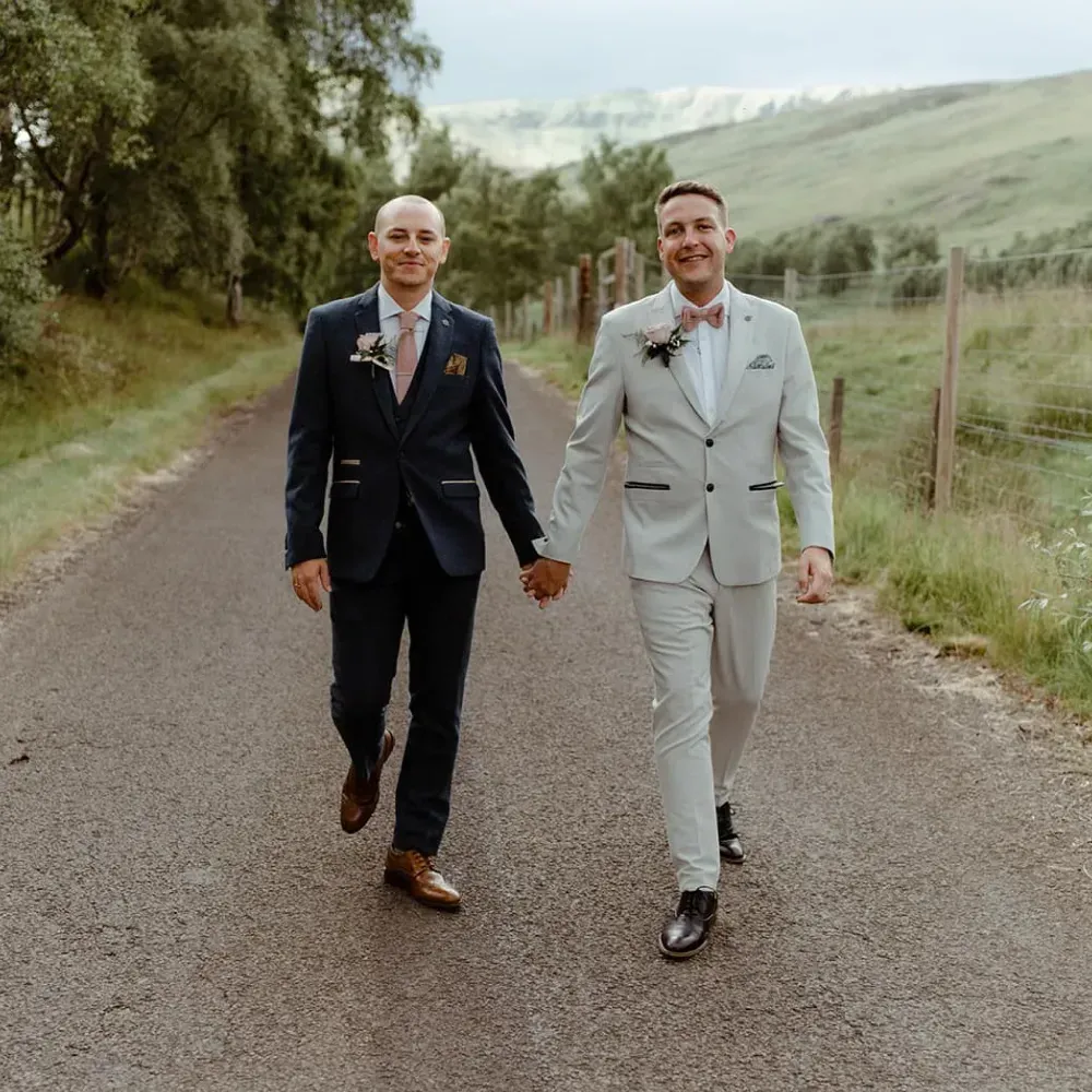 A happy wedding couple walking hand-in-hand along a road in the glen.
