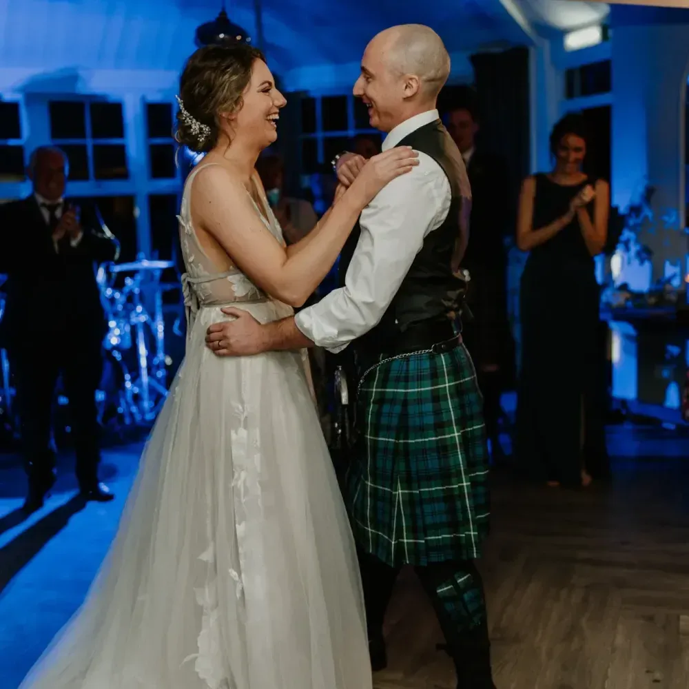 A happy wedding couple shares a joyful moment dancing together during their reception.