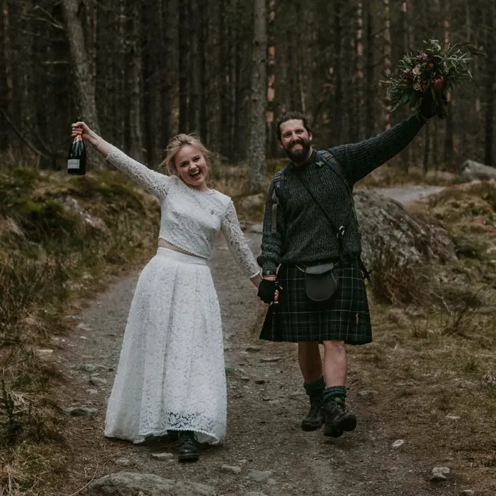 A happy wedding couple celebrates while walking together along a woodland path in the glen.