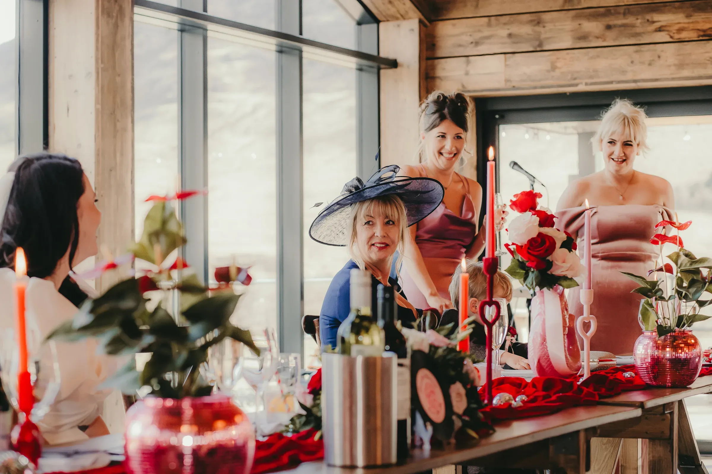 The wedding top table is beautifully dressed and set for dinner inside the barn, featuring the bride on the left and the wedding party on the right.