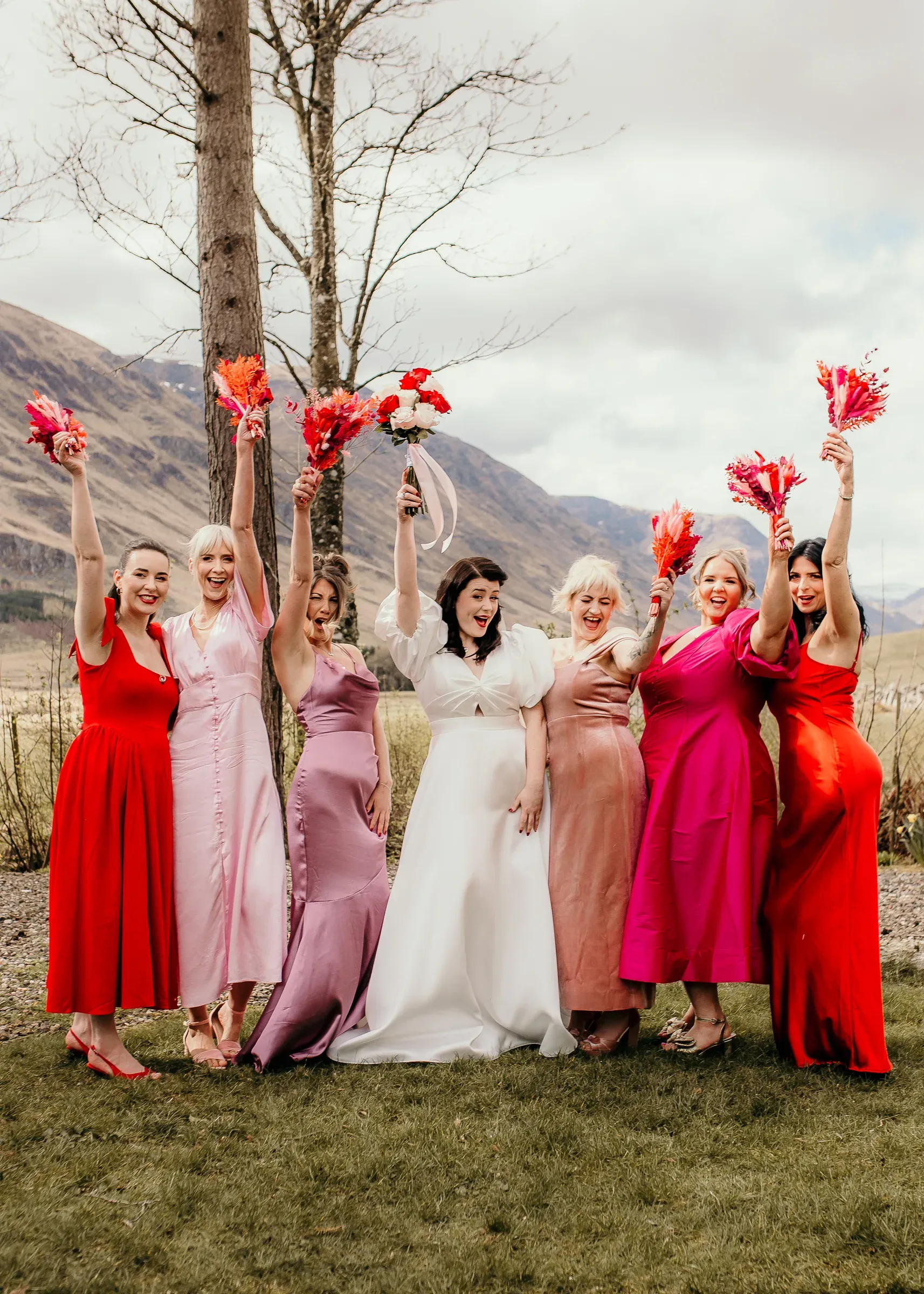 Meg and her bridal party pose outdoors in the glen, holding their flowers high in celebration.
