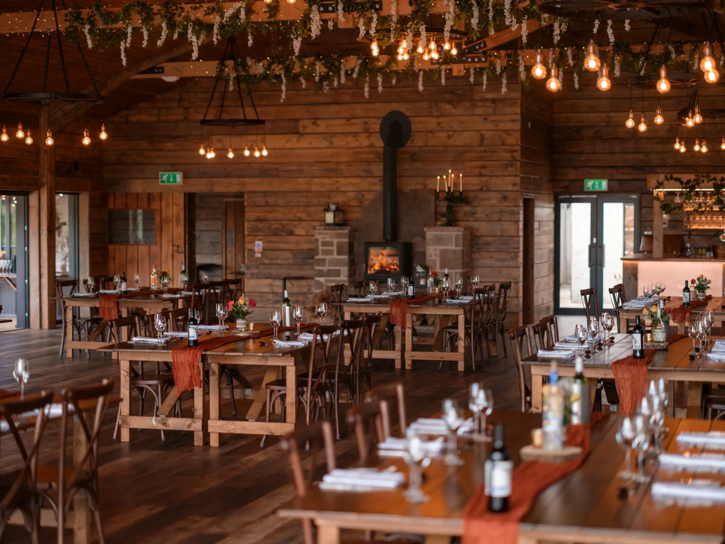 The interior of the barn is set for a wedding reception, featuring warm lighting and a cozy fireplace.