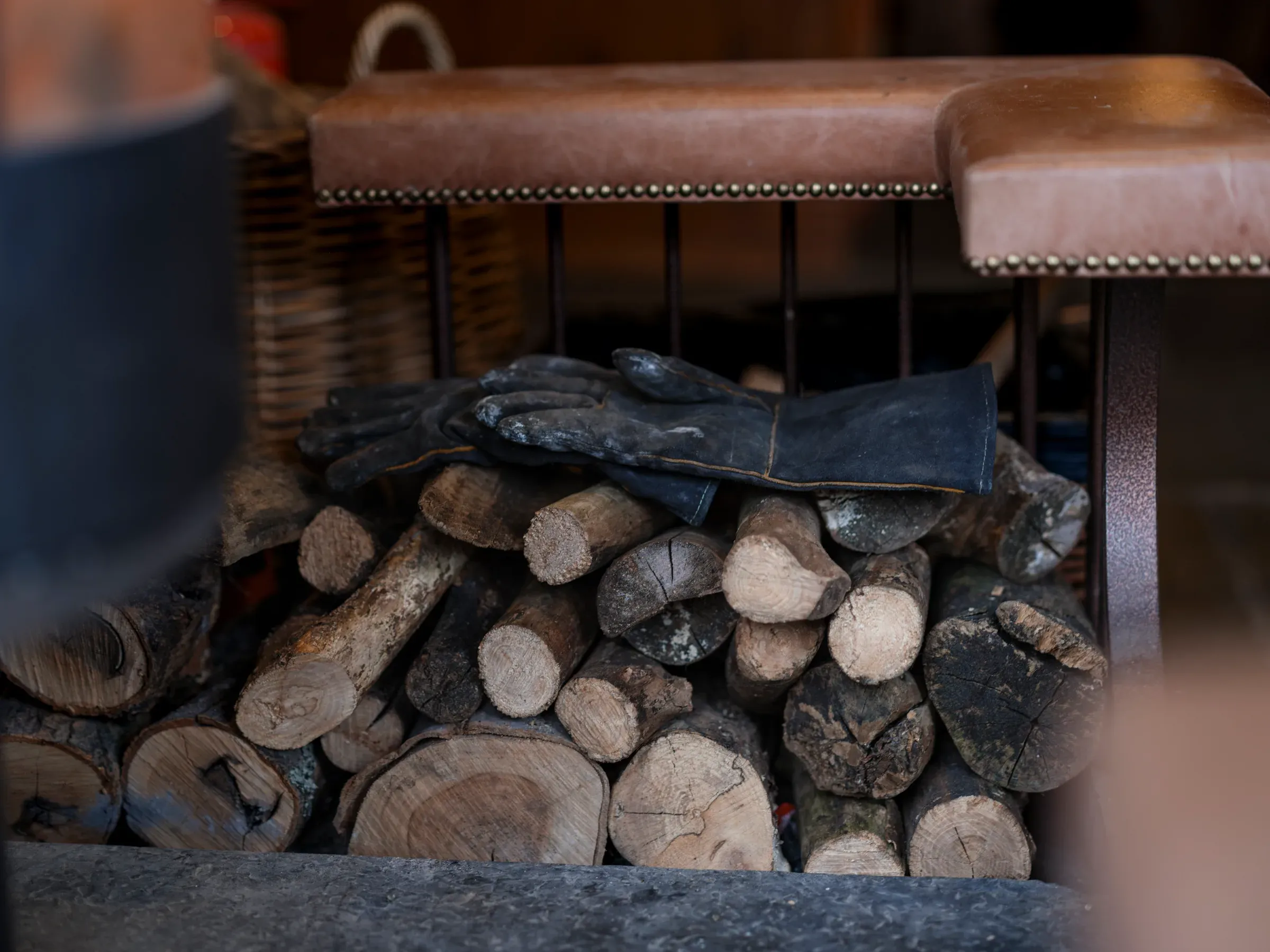 A staging shot featuring a stack of wood logs and fire gloves, highlighting the warm, fire-lit atmosphere of the venue.