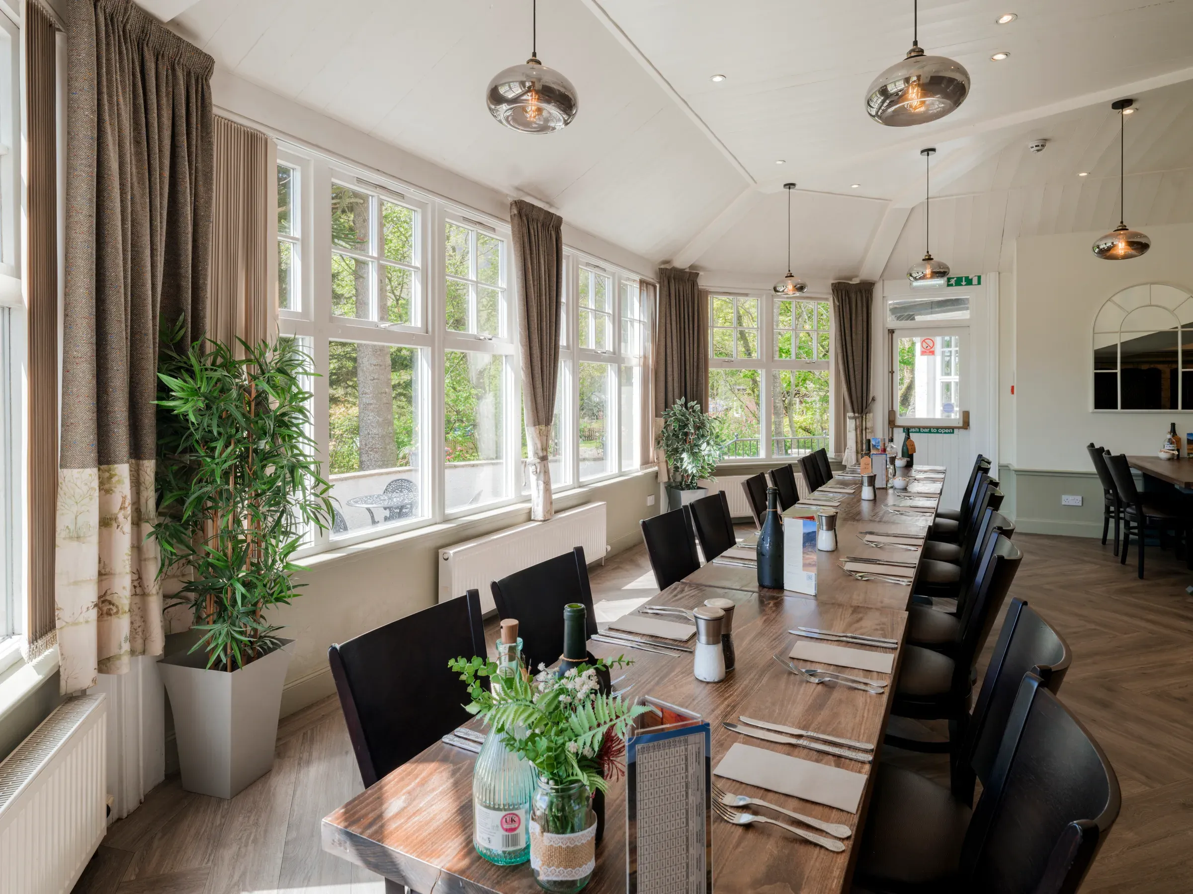 An empty restaurant dining area at Glenclova featuring long wooden tables set for guests.