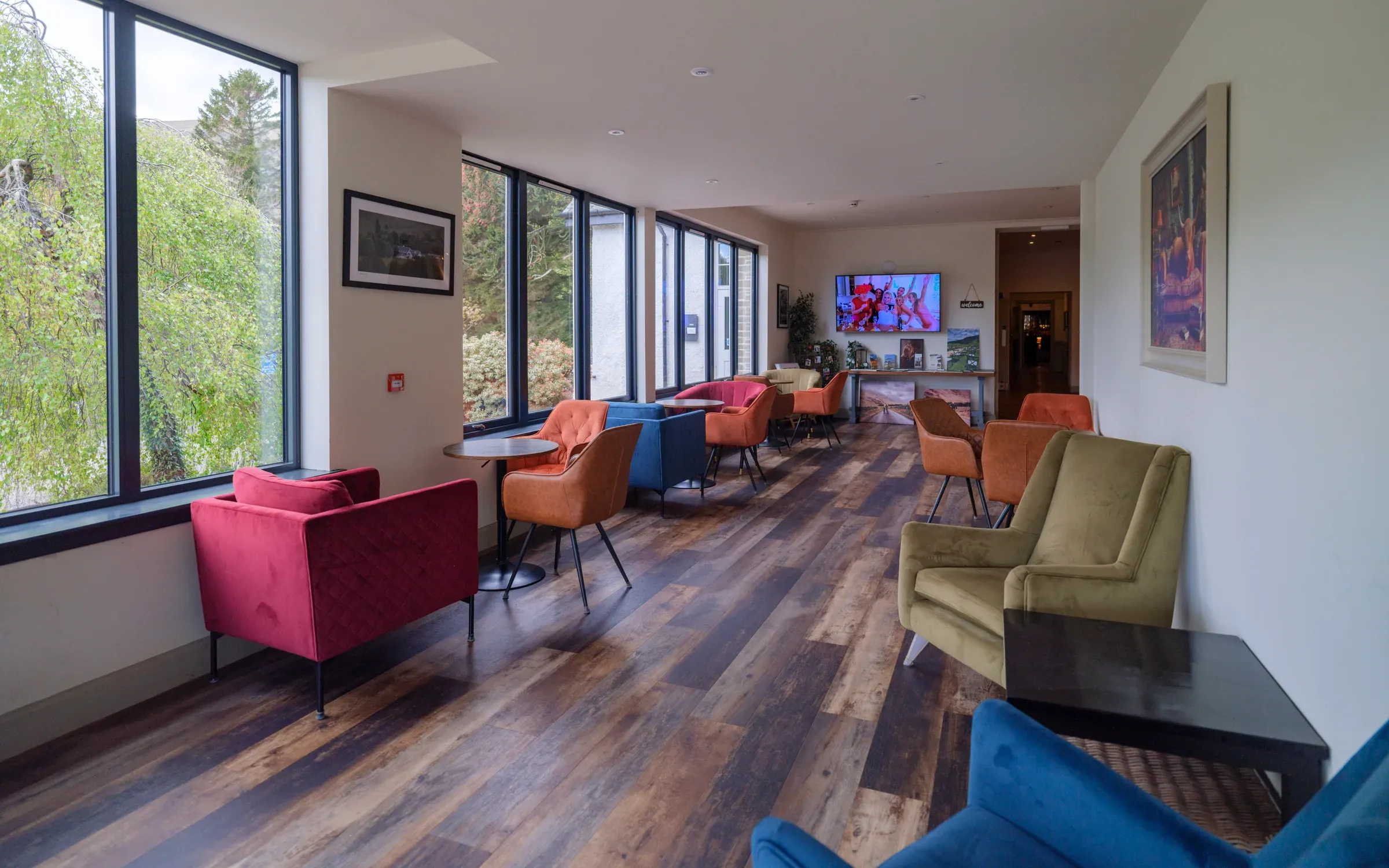 A view of the hotel entrance and interior lounge area featuring colourful armchairs and large windows.