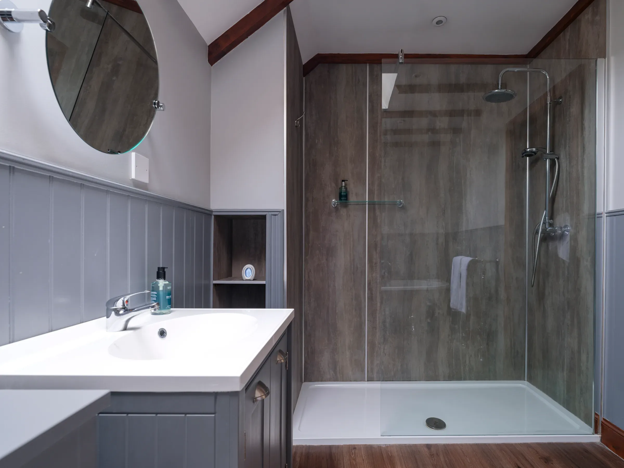 The interior of a modern bathroom at the Old Mill Lodge featuring a vanity sink and a walk-in shower.