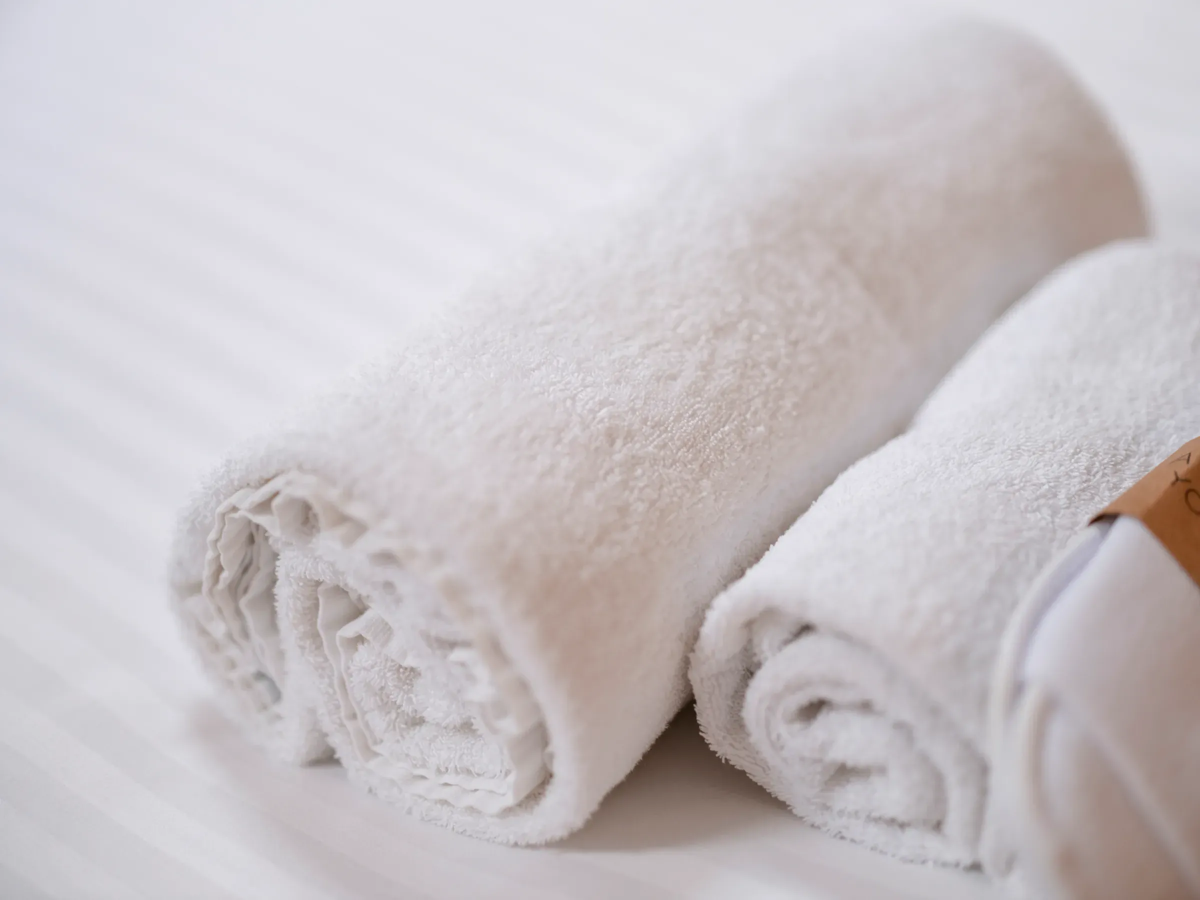 Two neatly rolled white towels resting on a bed to evoke a spa-like experience within the venue's accommodation.