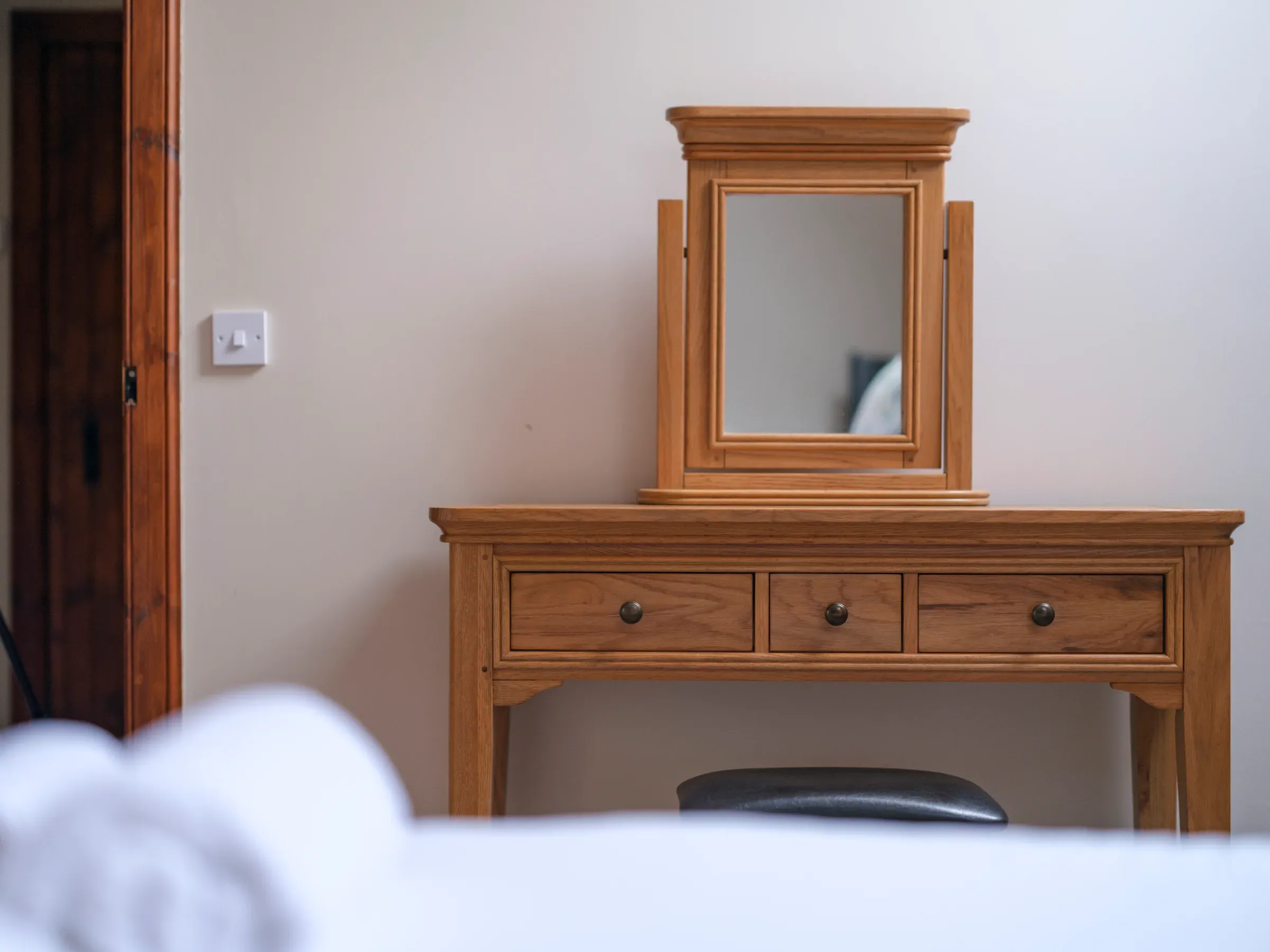 A wooden dressing table with a mirror inside a lodge, showcasing the venue's rustic wooden theme.