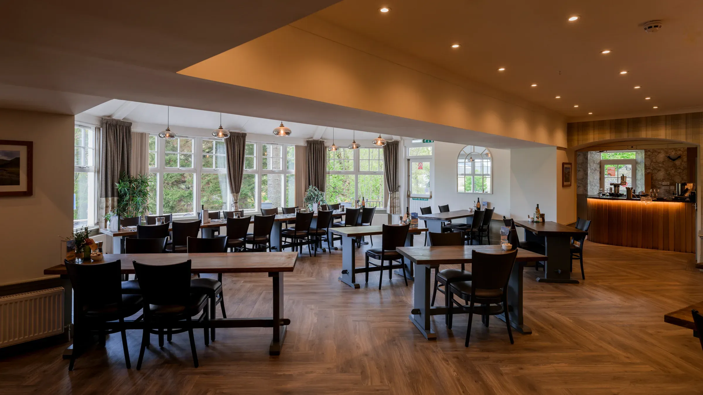 An empty restaurant space set up with wooden tables and chairs.