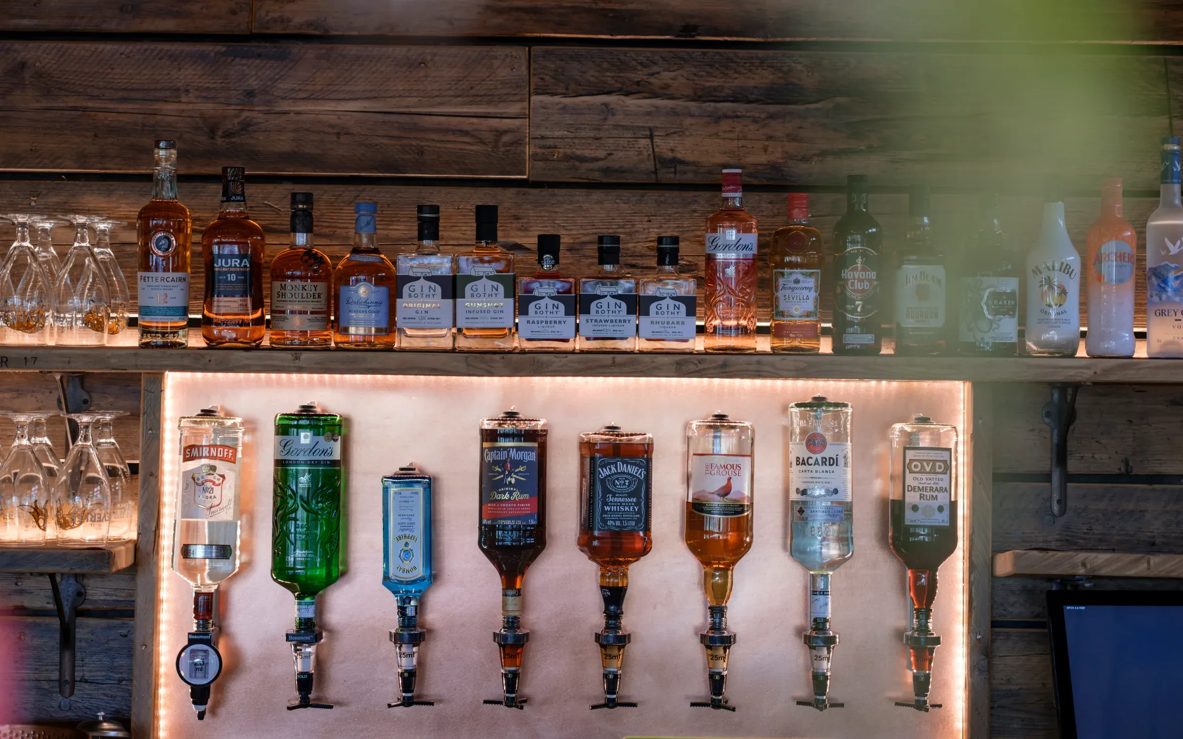 A selection of spirits and liqueurs displayed on a rustic wooden bar wall at the venue.