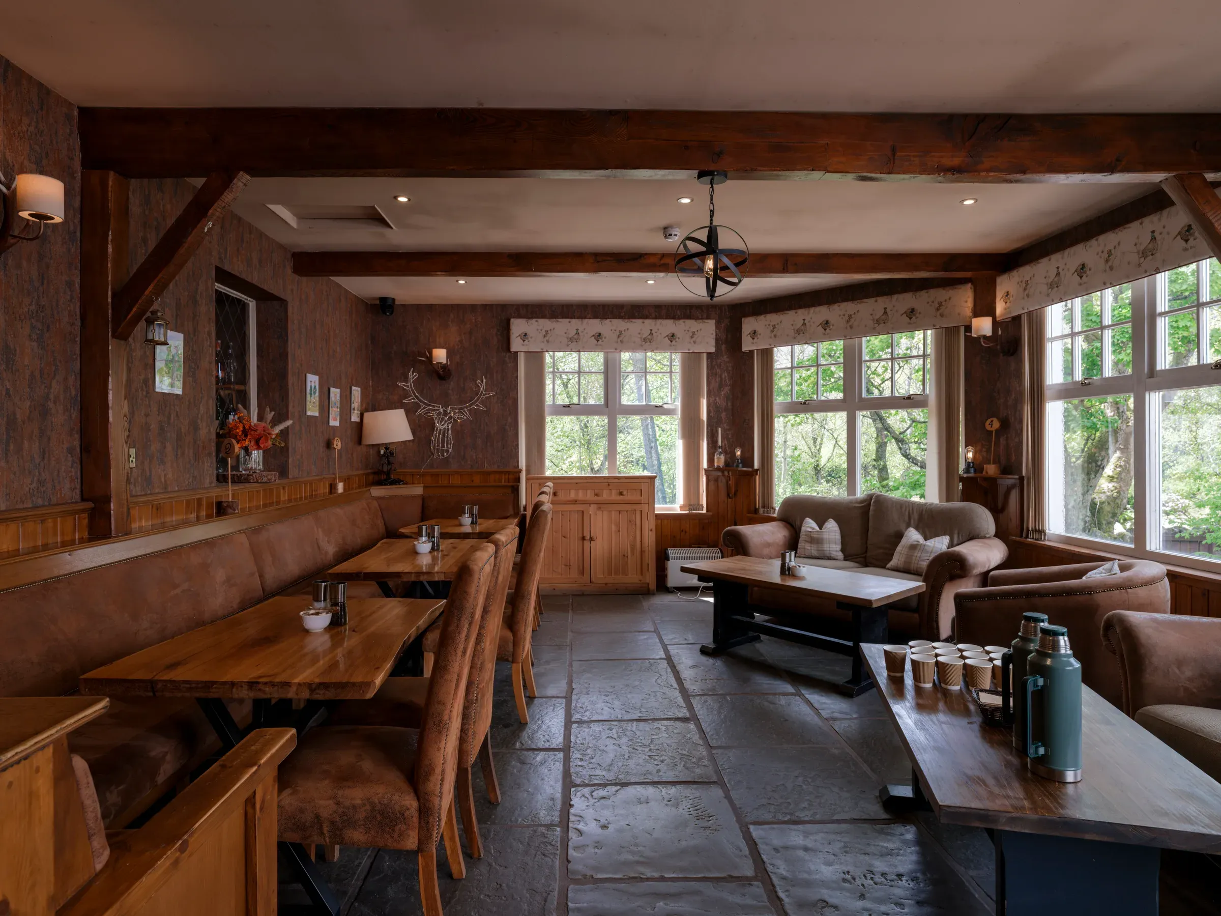 The interior of the bothy featuring rustic wooden tables and comfortable seating arrangements.