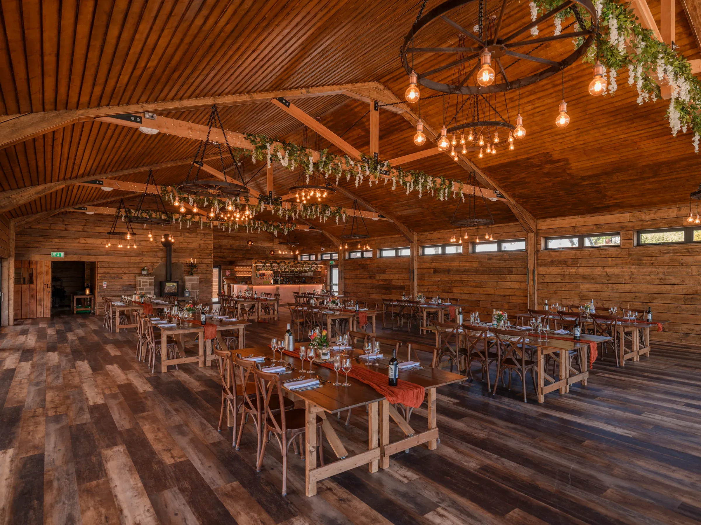 The Glenclova barn is staged for a wedding dinner with rustic wooden tables and warm lighting.
