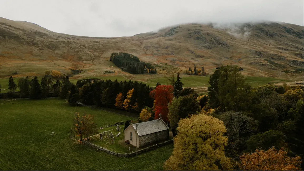 An aerial view showing the exterior of the kirk nestled within the Scottish Highland landscape.