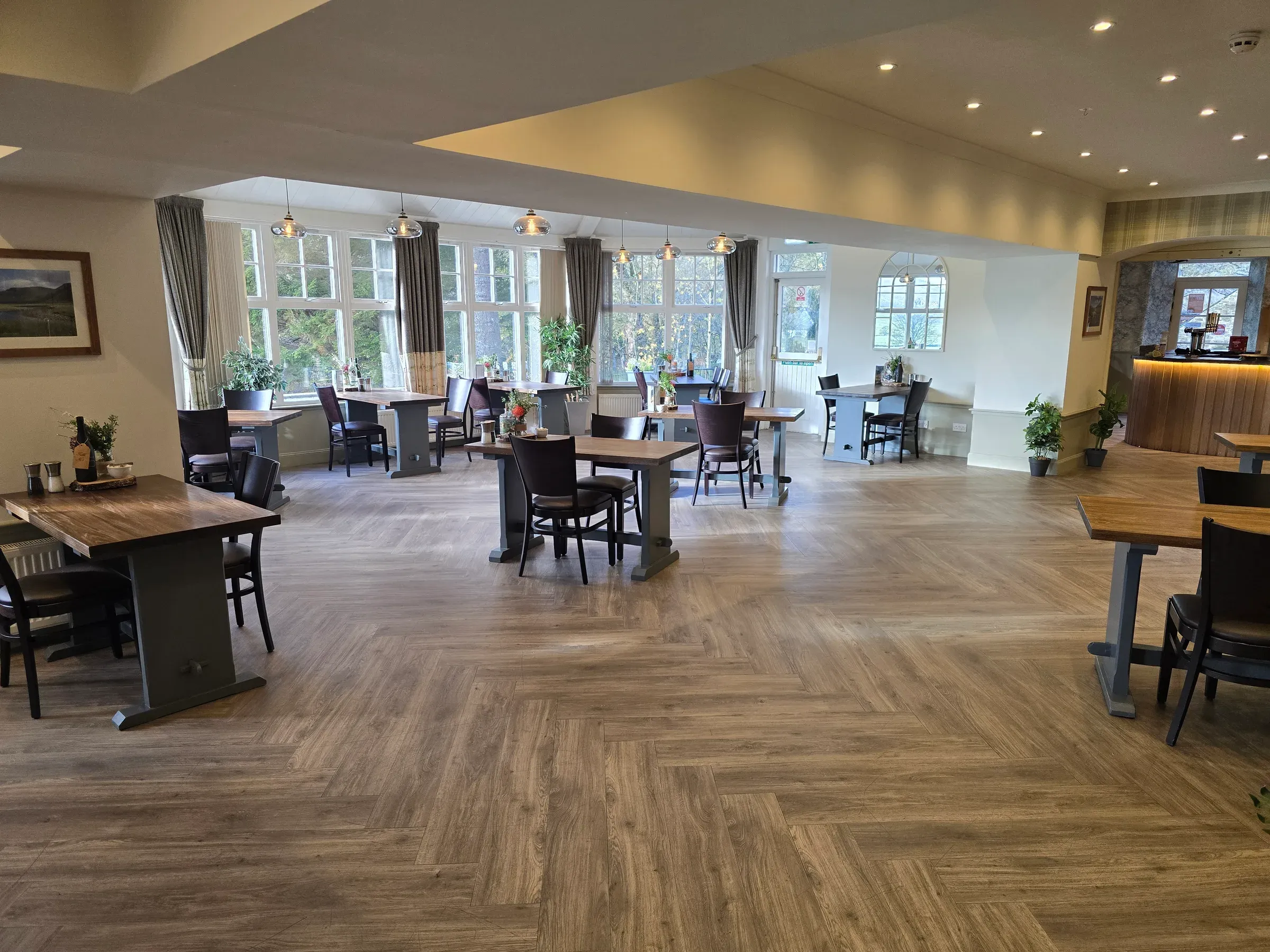 A view of the spacious restaurant dining area at Glenclova, featuring wooden tables and chairs set against large windows.