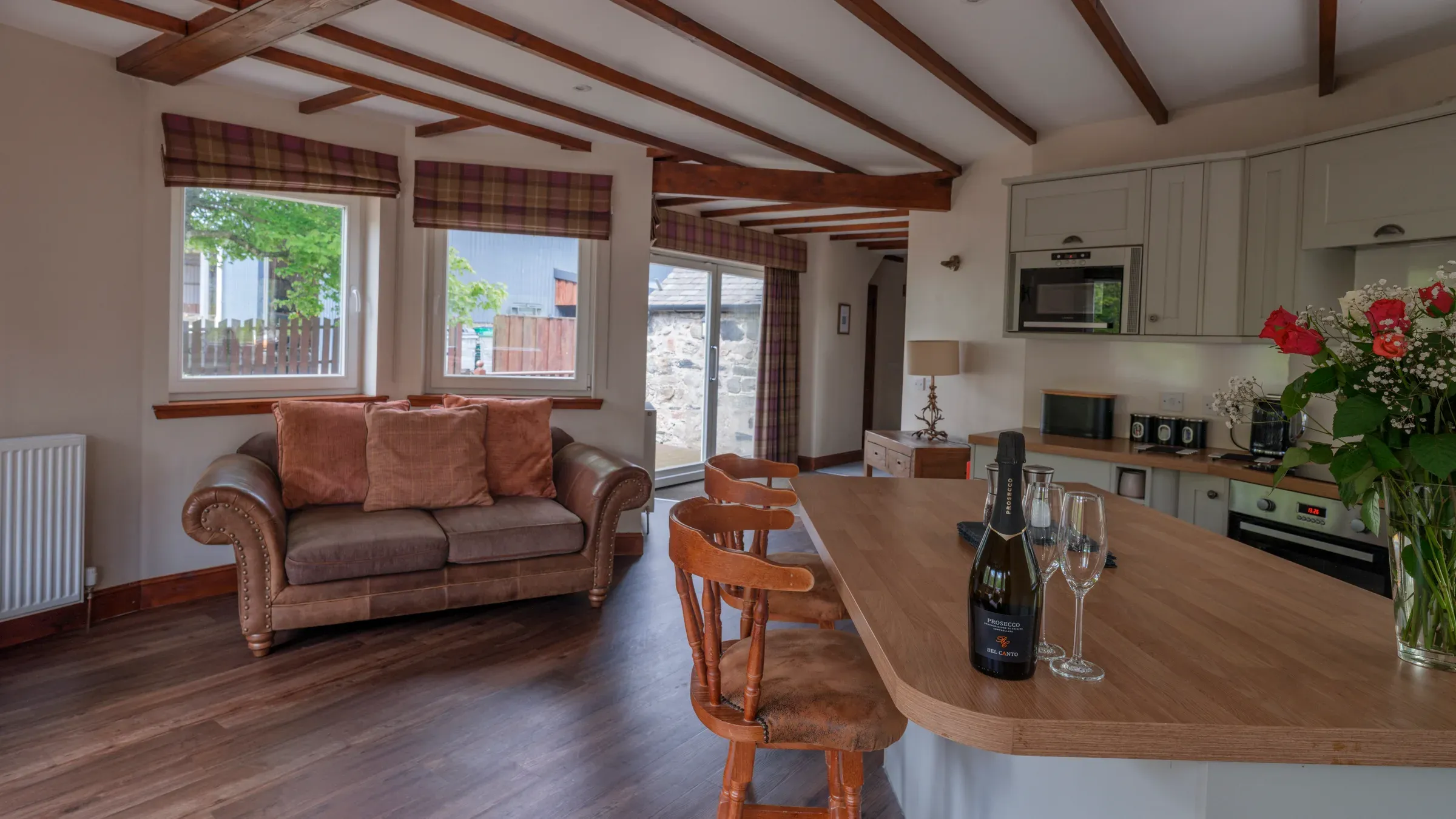 An interior view of a lodge house featuring a comfortable seating area and a kitchen island set with prosecco and glasses.