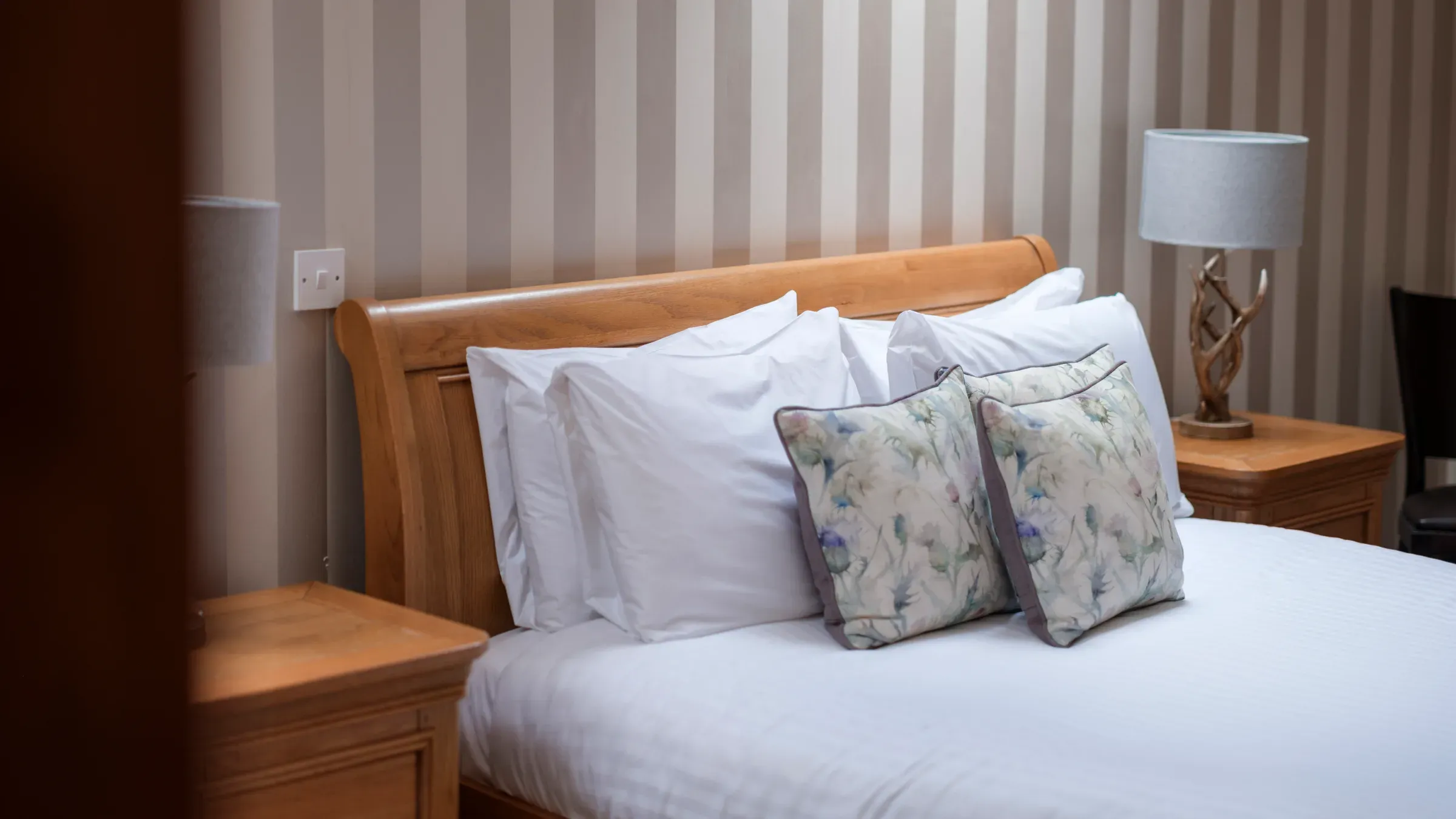 A close-up interior shot of a lodge bedroom featuring a wooden bed frame and decorative cushions.