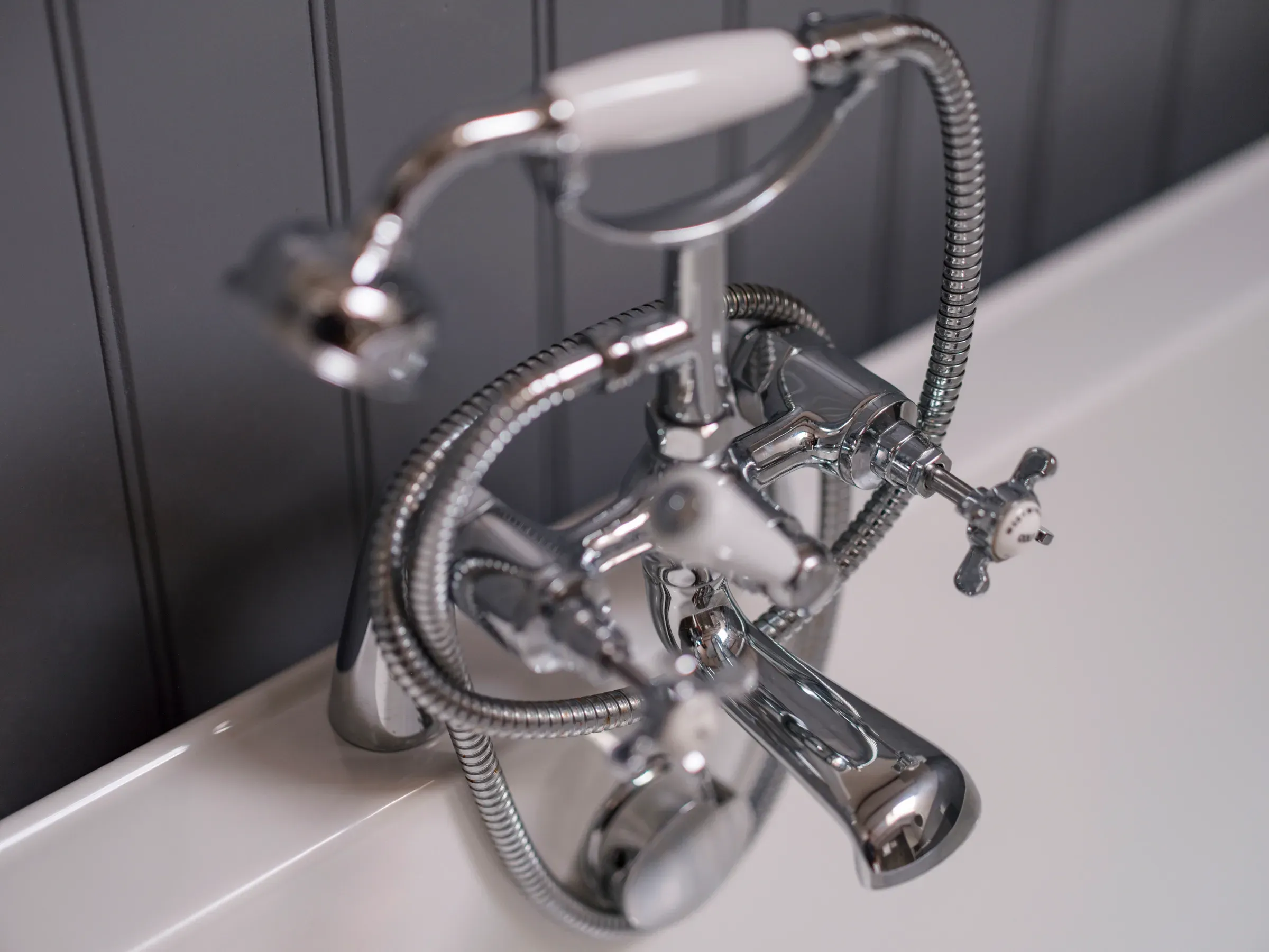 A close-up detail shot of a vintage-style chrome bathtub faucet in a lodge bathroom.