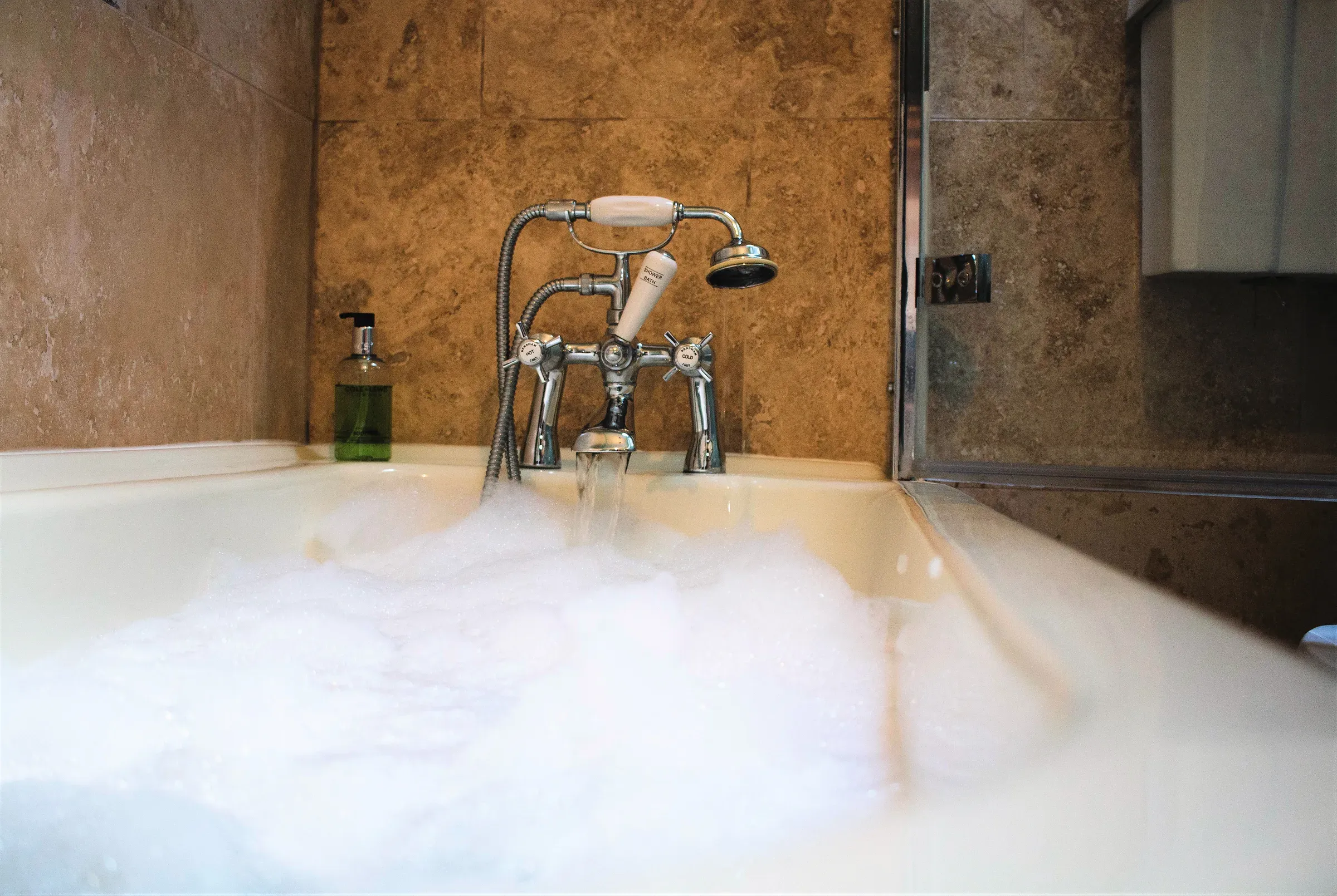 A bubble-filled bathtub with vintage-style fixtures inside the Manse B&B cottage.